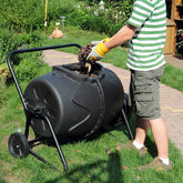 Person adding kitchen waste into a Removable Rotary Compost Bucket for efficient composting in a garden.