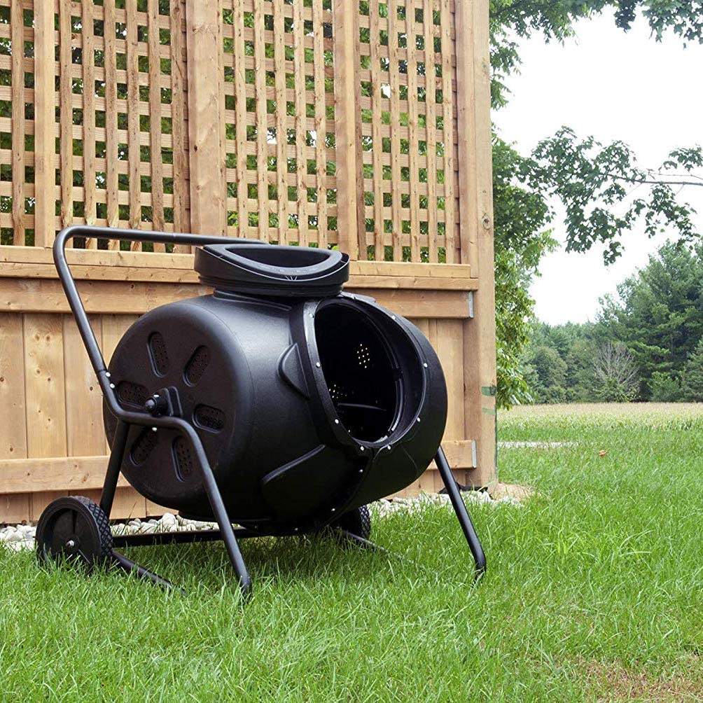 Person adding kitchen waste into a Removable Rotary Compost Bucket for efficient composting in a garden.