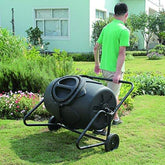 Person adding kitchen waste into a Removable Rotary Compost Bucket for efficient composting in a garden.